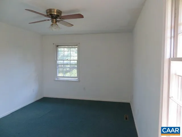 an empty room with a window and a fan