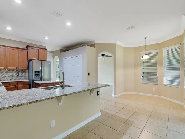 a large kitchen with kitchen island a large counter top space a sink a refrigerator and a granite counter tops