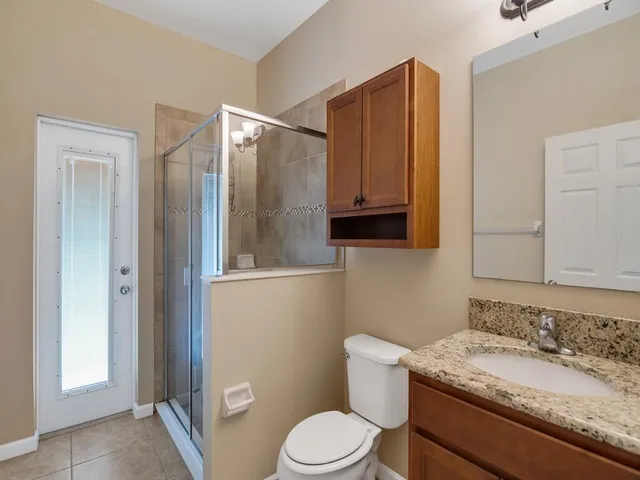 a bathroom with a granite countertop sink toilet and mirror