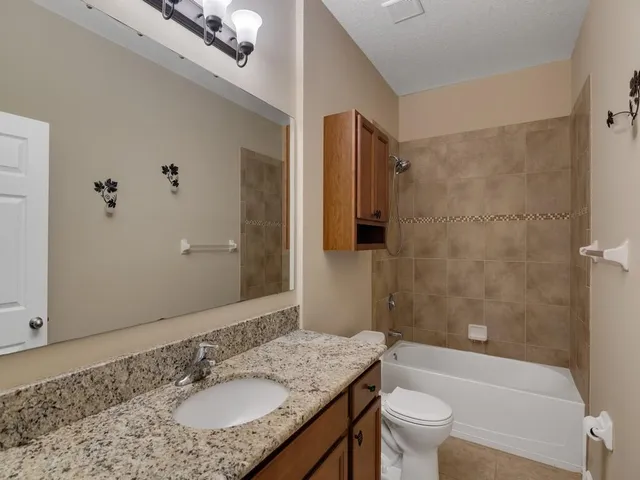 a bathroom with a granite countertop sink toilet and shower