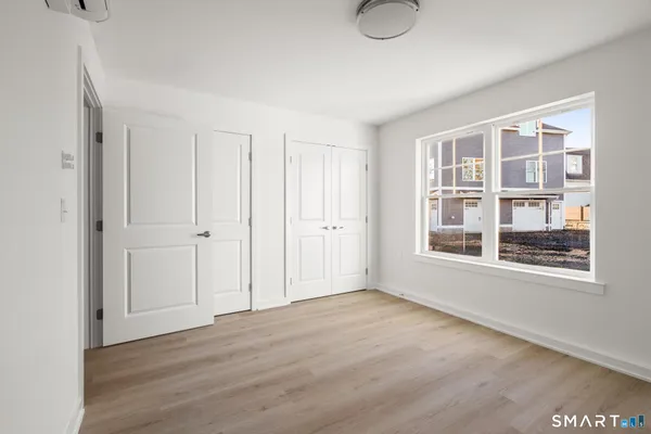 a view of an empty room with wooden floor and windows