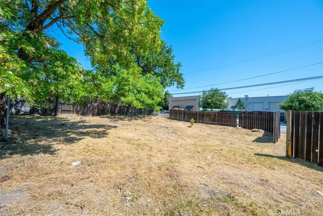 a backyard of a house with table and chairs a barbeque with potted plants and large trees