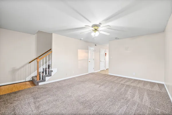 a view of an empty room with chandelier fan