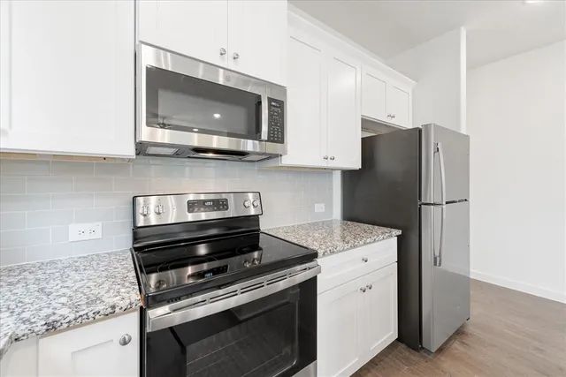 a kitchen with stainless steel appliances granite countertop a sink and a white cabinets