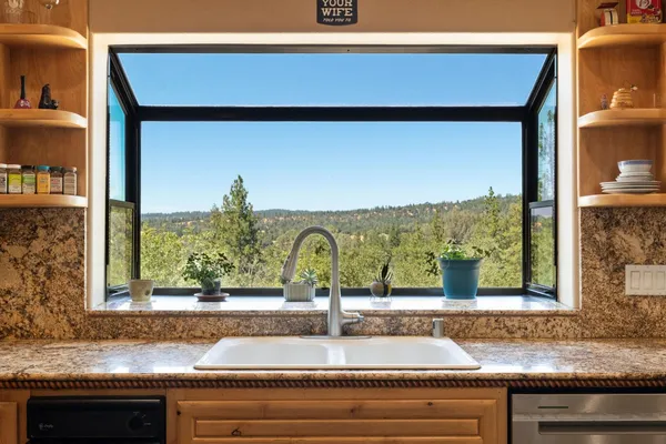 a large kitchen with stainless steel appliances kitchen island granite countertop a large stove top oven a sink dishwasher and a fireplace with wooden floor