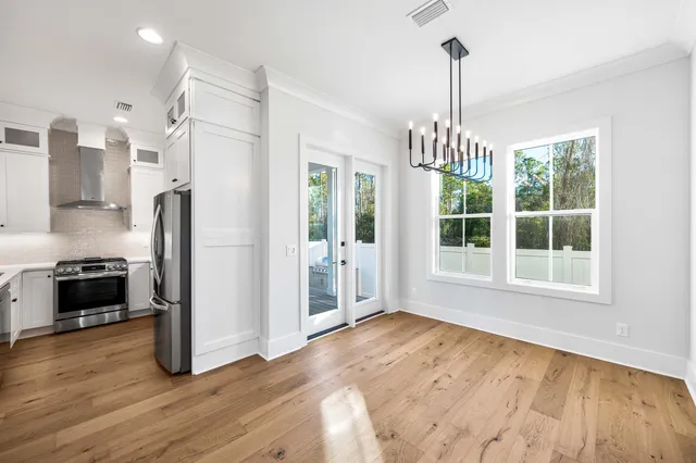 a view of empty room with wooden floor and a kitchen