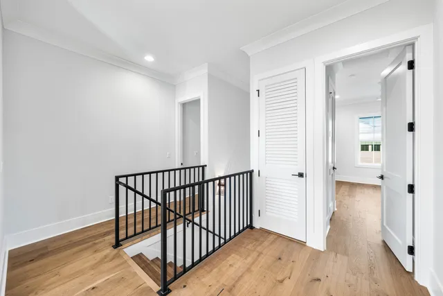 a view of a hallway with wooden floor and a bathroom
