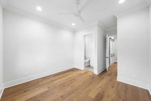 an empty room with wooden floor and a ceiling fan
