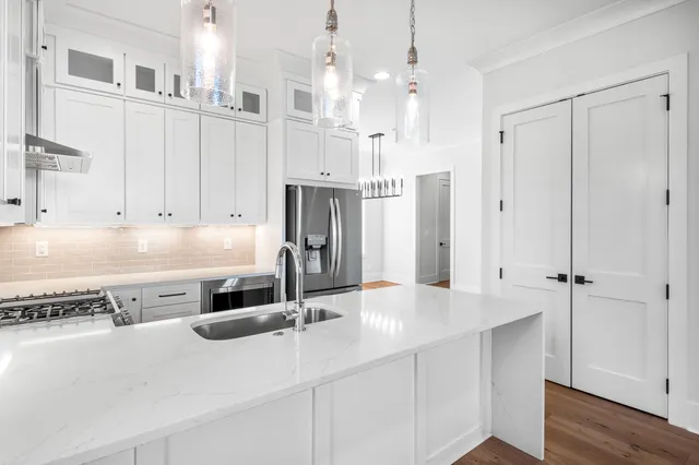 a kitchen with stainless steel appliances granite countertop a sink dishwasher and white cabinets with wooden floor