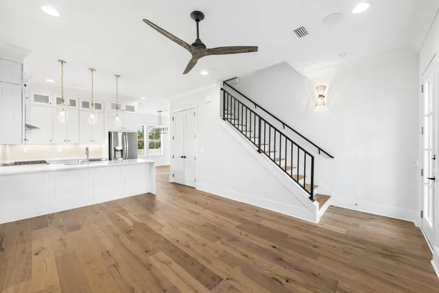 a view of empty room with wooden floor and kitchen view