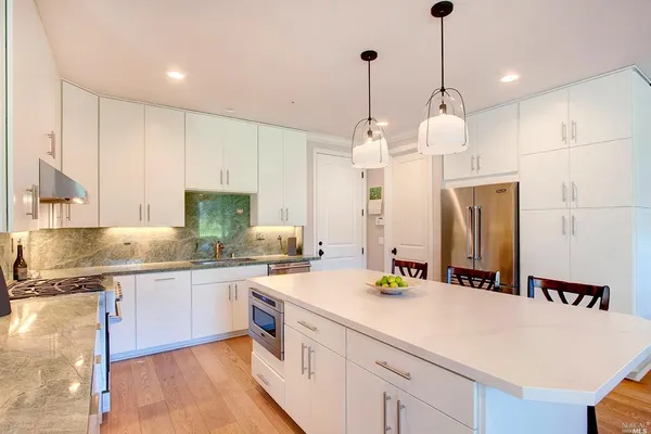 a large kitchen with stainless steel appliances kitchen island granite countertop a sink a stove and a wooden floors