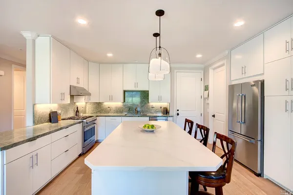 a large kitchen with kitchen island a refrigerator a stove a sink a dining table and chairs