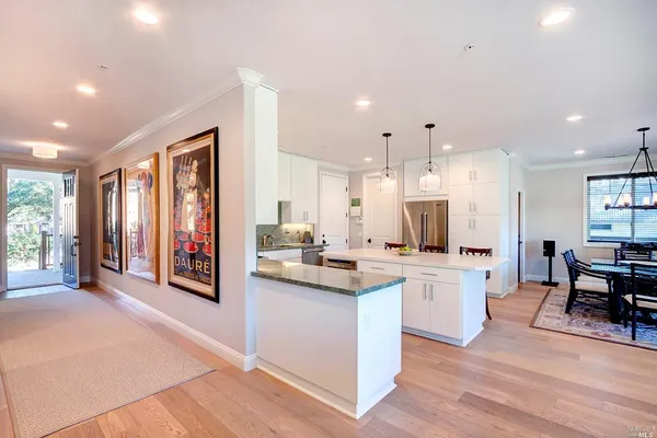 a large kitchen with cabinets chairs and wooden floor