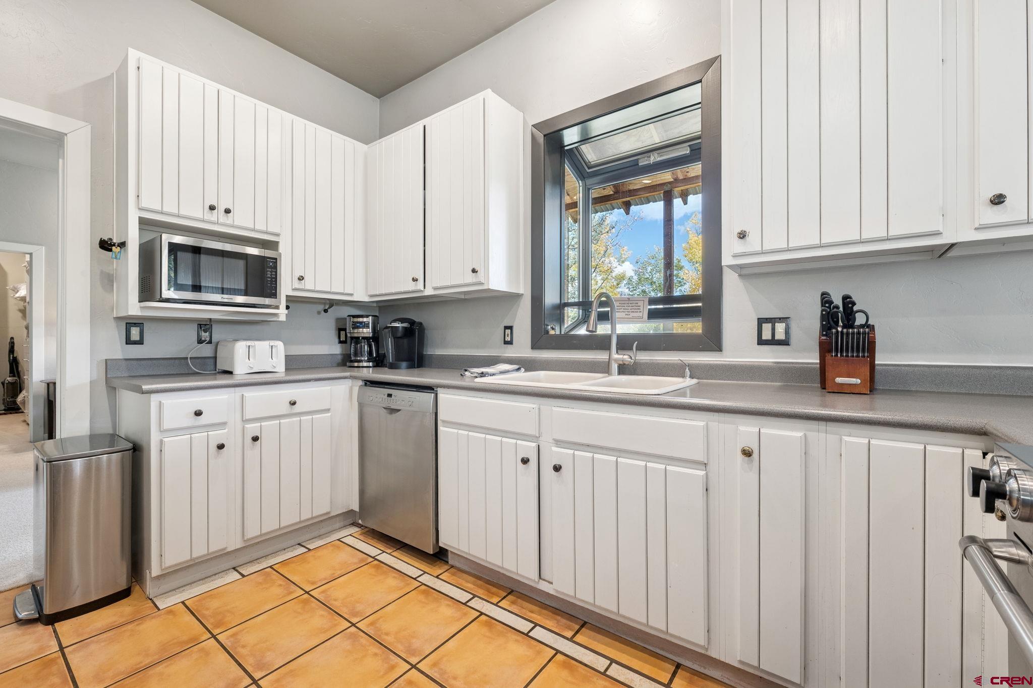 333 Beaver Circle Durango, CO 81301 - Photo 19 of 45 a kitchen with granite countertop white cabinets stainless steel appliances a sink and a window