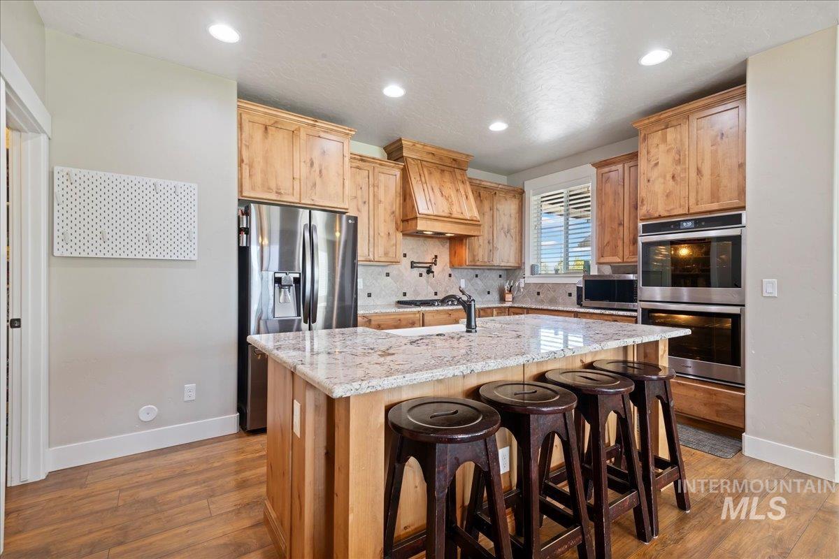 6091 East Path Drive Nampa, ID 83687 - Photo 11 of 33 Kitchen featuring tasteful backsplash, light stone countertops, stainless steel appliances, recessed lighting, and custom exhaust hood