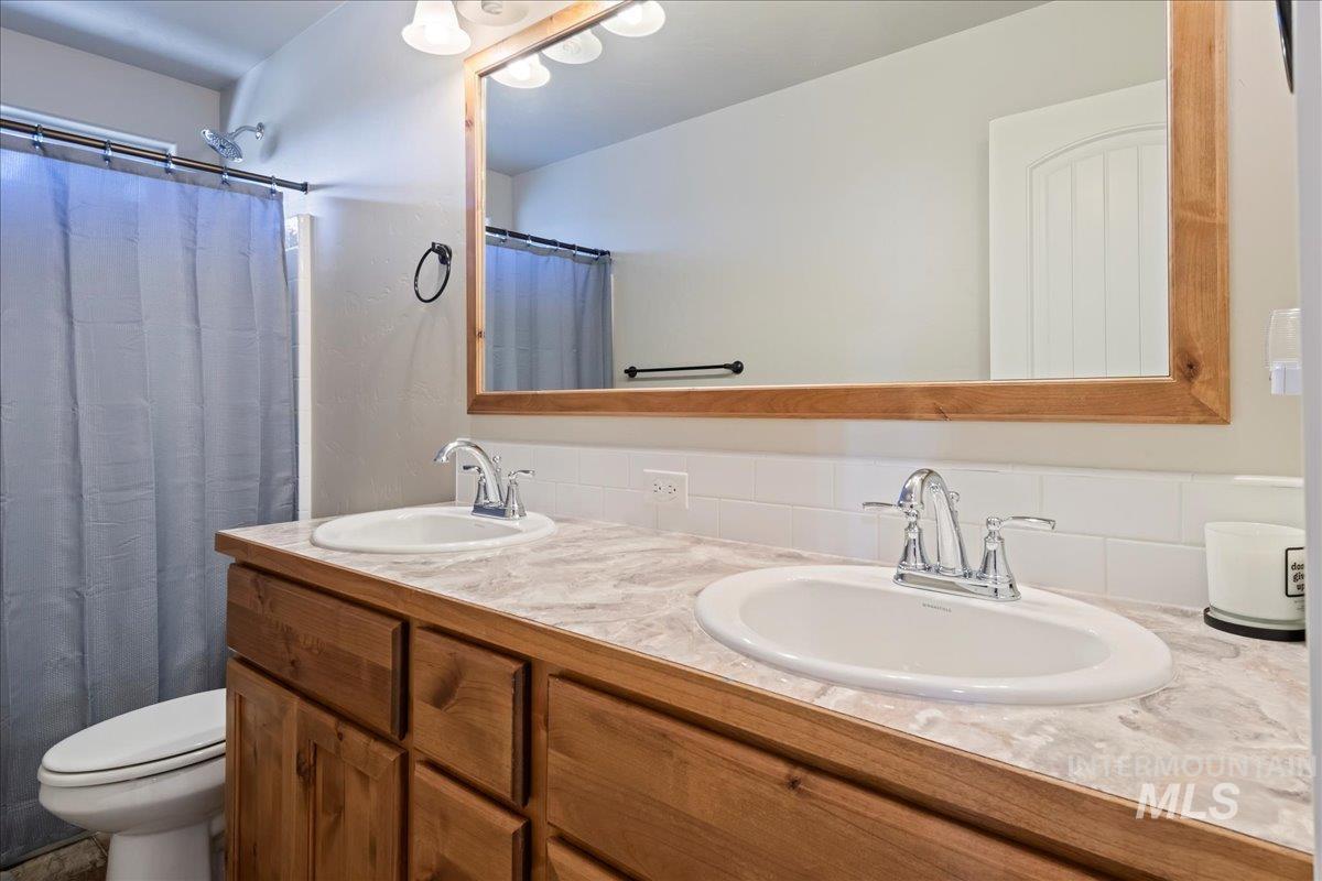 6091 East Path Drive Nampa, ID 83687 - Photo 24 of 33 Bathroom with double vanity, decorative backsplash, and curtained shower