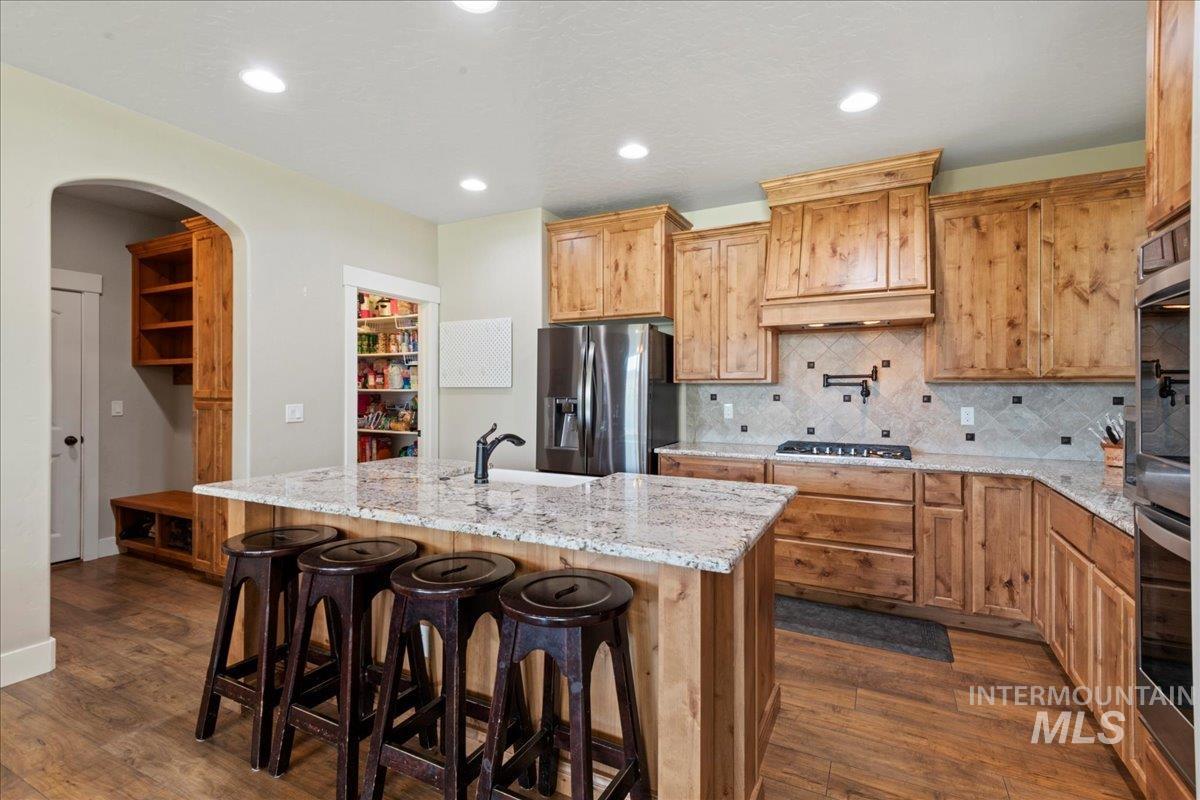 6091 East Path Drive Nampa, ID 83687 - Photo 10 of 33 Kitchen with backsplash, light stone countertops, arched walkways, recessed lighting, and dark wood finished floors
