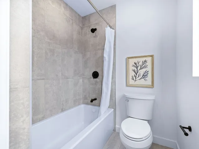 a white toilet sitting next to a bath tub