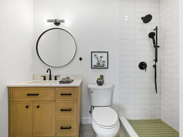 a bathroom with a toilet a sink a mirror and shower