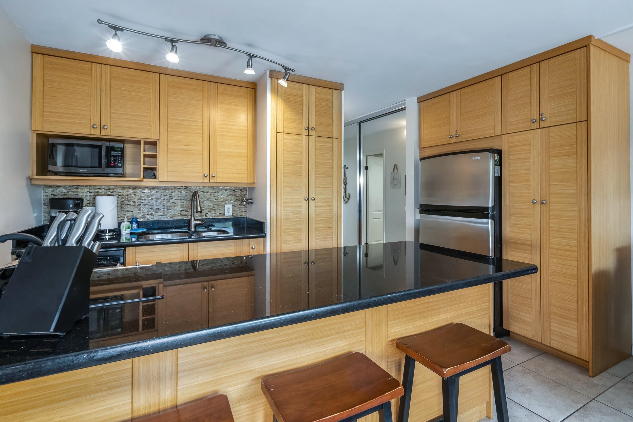 2191 South Kihei Road, Unit 1110 Kihei, HI 96753 - Photo 6 of 20 a kitchen with stainless steel appliances wooden cabinets and a refrigerator
