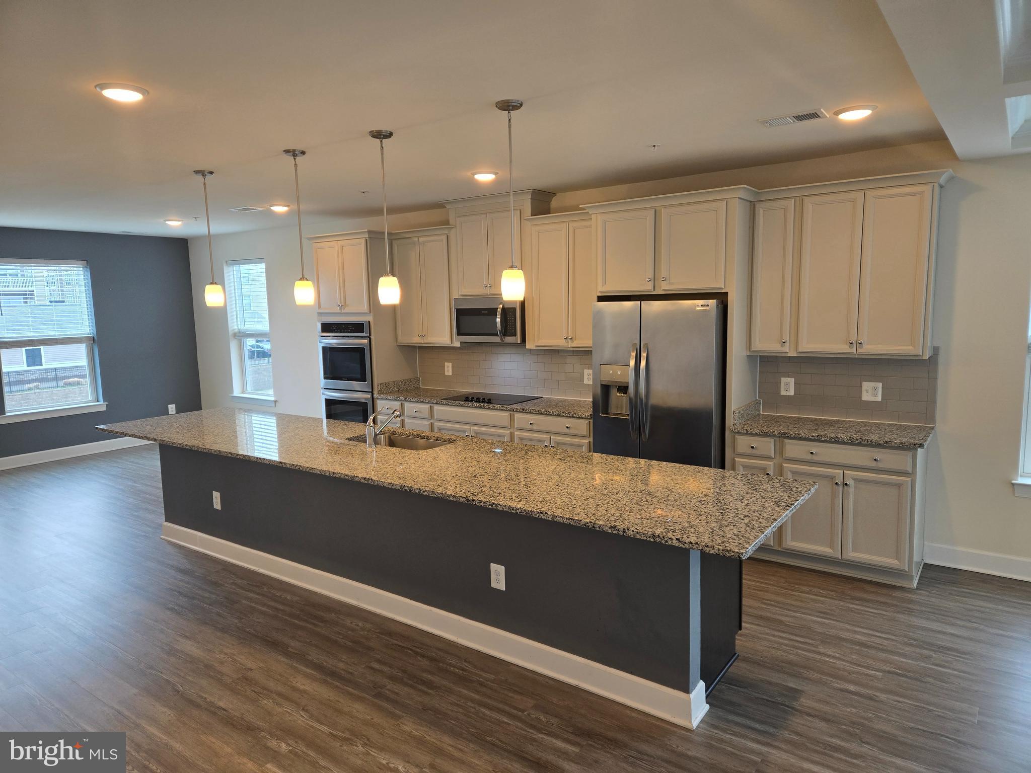 a large kitchen with stainless steel appliances kitchen island a large counter top and a wooden floors