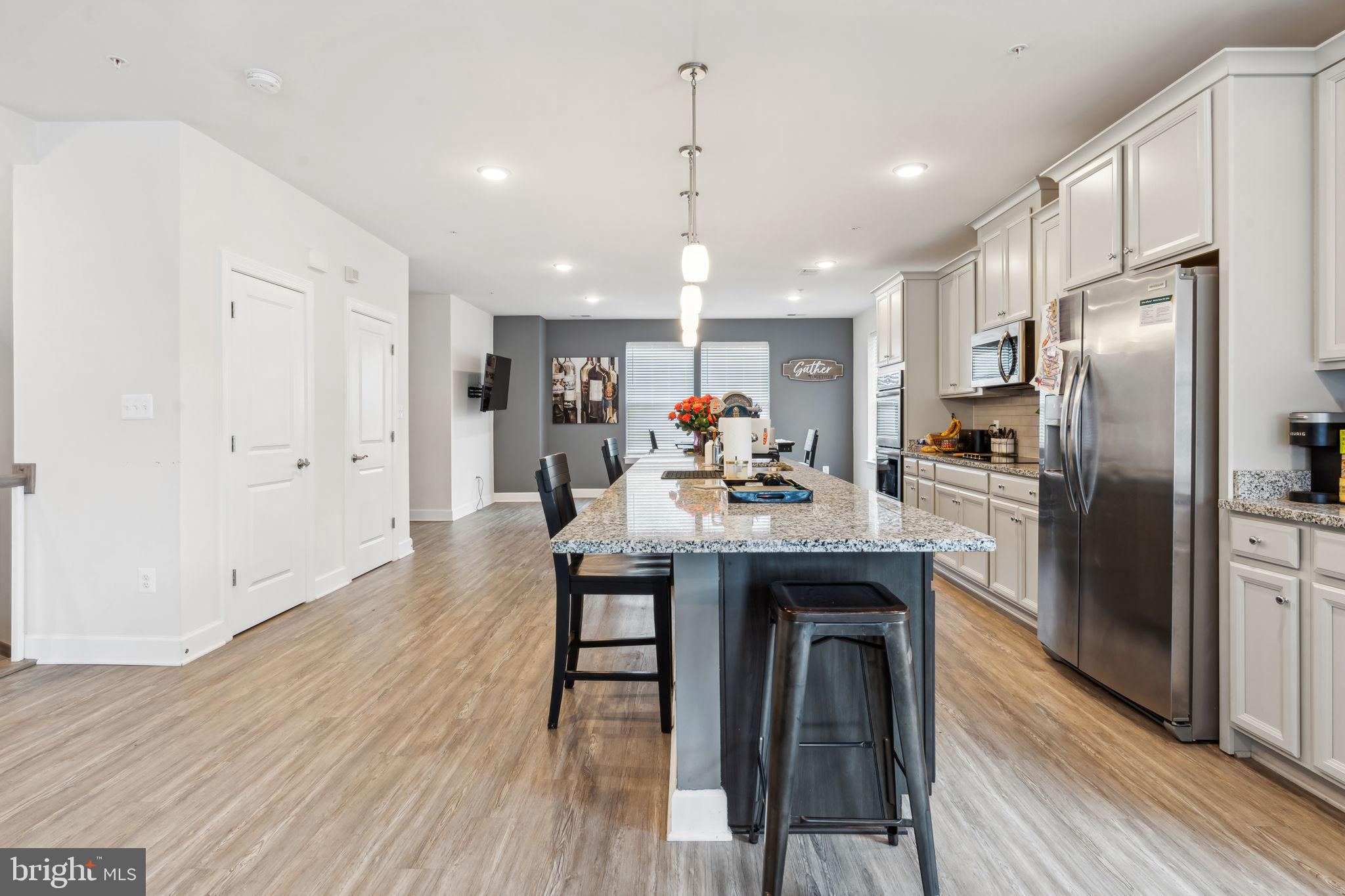 7635 Stemhart Lane Hanover, MD 21076 - Photo 8 of 28 a kitchen with stainless steel appliances granite countertop a refrigerator a sink dishwasher a stove and a dining table with wooden floor