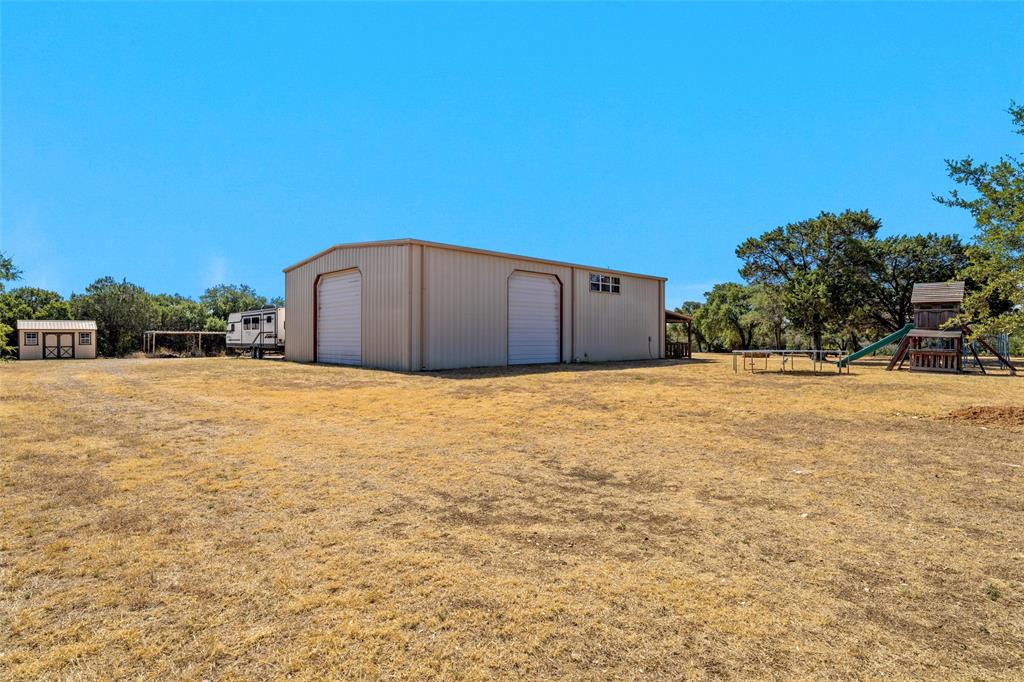 311 Cedar Ridge Drive China Spring, TX 76633 - Photo 21 of 28 View of yard featuring a garage, an outbuilding, and a playground