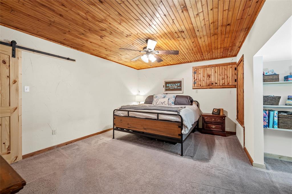 311 Cedar Ridge Drive China Spring, TX 76633 - Photo 8 of 28 Carpeted bedroom with a barn door, wooden ceiling, and ceiling fan