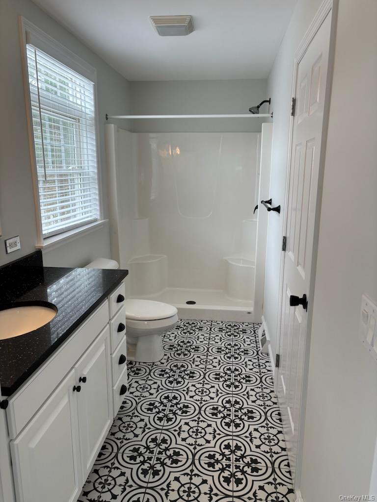 1661 Old Country Road, Unit 539 Riverhead, NY 11901 - Photo 11 of 26 a bathroom with a granite countertop sink a toilet a mirror a shower and a window
