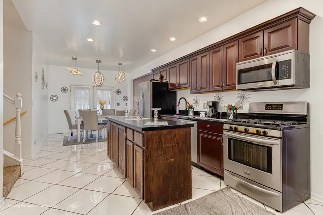 a kitchen with stainless steel appliances granite countertop a stove top oven a sink and a refrigerator