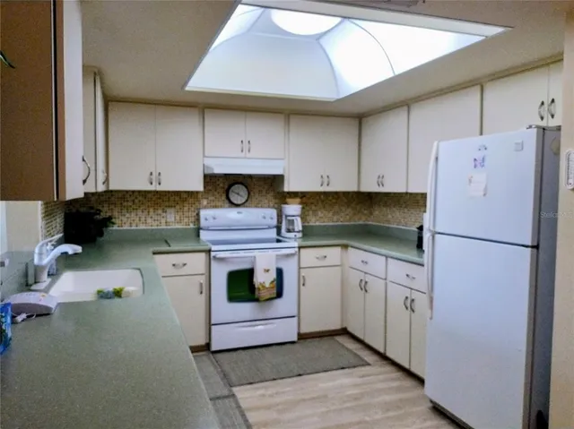 a kitchen with stainless steel appliances a sink a refrigerator and wooden floor