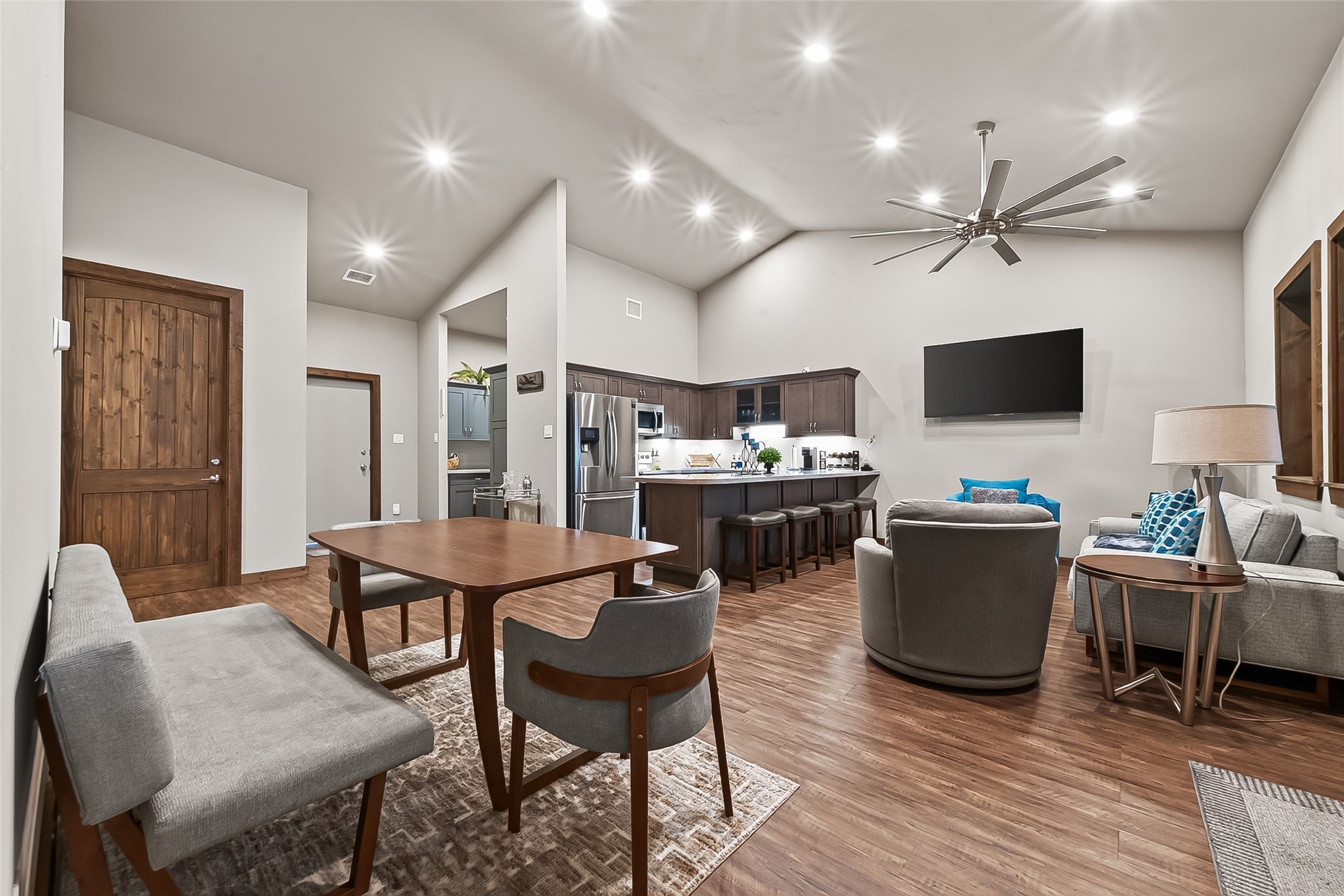 22610 Cessna Road Needville, TX 77461 - Photo 12 of 37 Cozy living area with modern furnishings, featuring a sleek wall-mounted TV and an inviting seating arrangement. Adjacent to the kitchen with a stylish breakfast bar, perfect for entertaining.