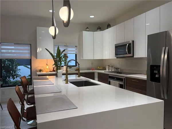 a large kitchen with stainless steel appliances a large counter top a stove a chimney a sink and a refrigerator