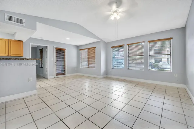 a view of an empty room with window and chandelier fan