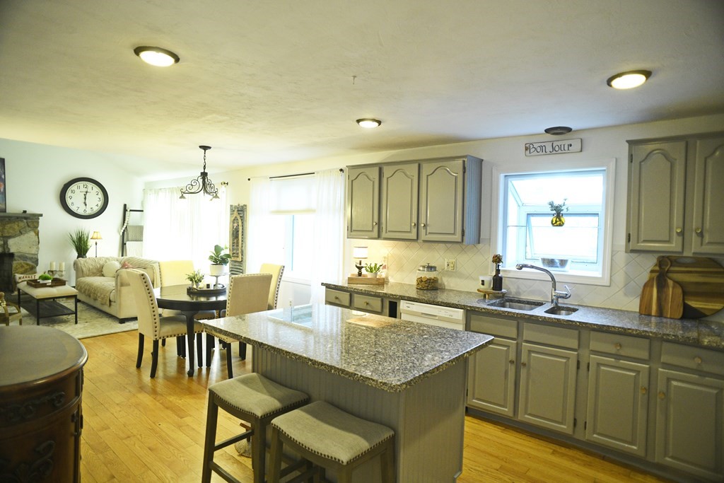 72 Heritage Drive Lowell, MA 01852 - Photo 4 of 29 a kitchen with granite countertop a dining table chairs and white cabinets