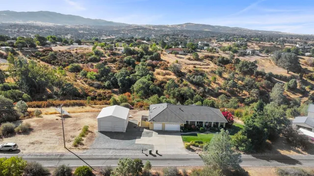 an aerial view of a house with a yard and mountain view in back