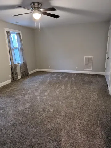 en empty room with windows and ceiling fan