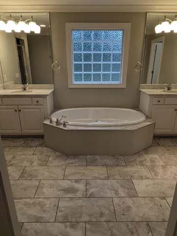 a bathroom with a tub a sink a mirror and a toilet