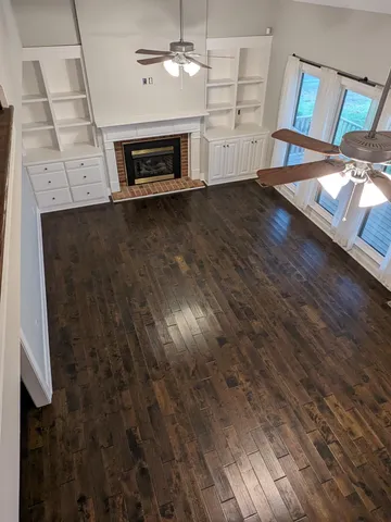an empty room with wooden floor fireplace and windows