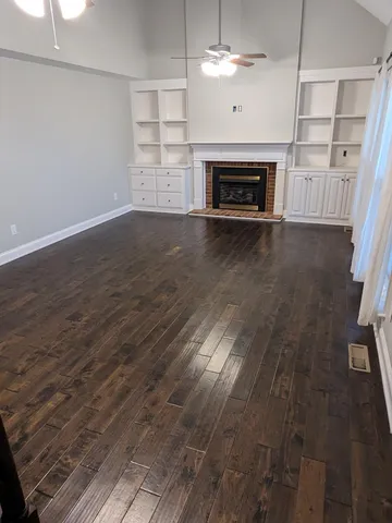 an empty room with wooden floor fireplace and windows