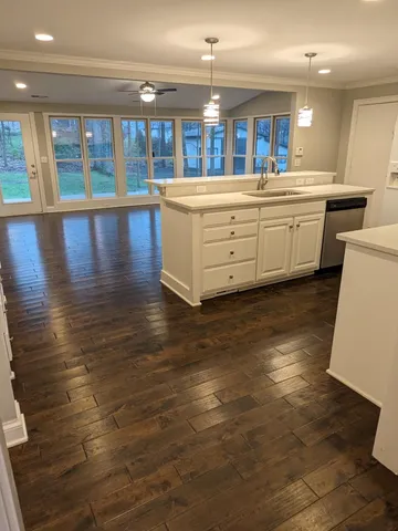 a large white kitchen with kitchen island granite countertop a large window and a sink