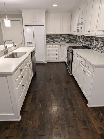 a kitchen with granite countertop white cabinets and white appliances