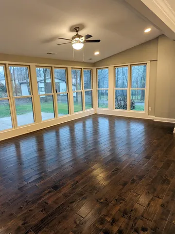 a view of an empty room with wooden floor and a window