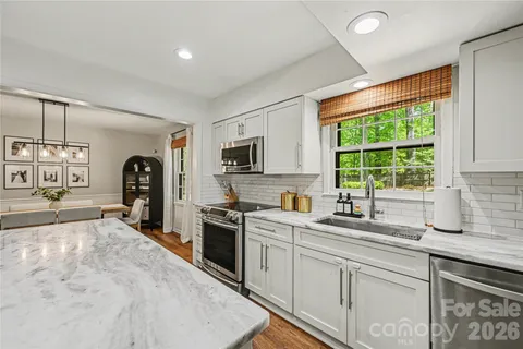 a kitchen with stainless steel appliances granite countertop a sink stove refrigerator and cabinets