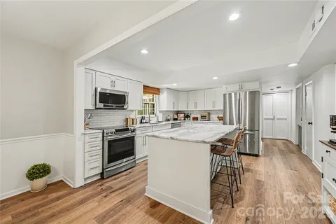 a kitchen with stainless steel appliances kitchen island granite countertop a stove and a sink
