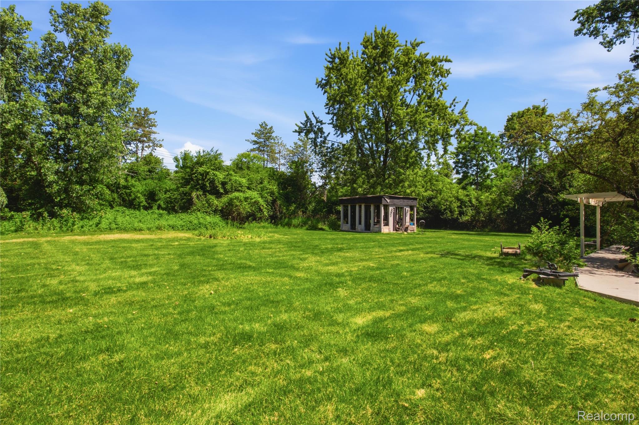 3812 Terrybrook Road West Bloomfield, MI 48322 - Photo 31 of 43 Expansive lawn area featuring a detached structure, a white pergola, and mature trees