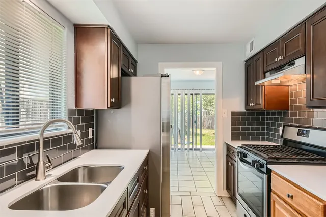 a kitchen with kitchen island granite countertop a sink and a refrigerator