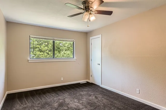 an empty room with a window and a fan
