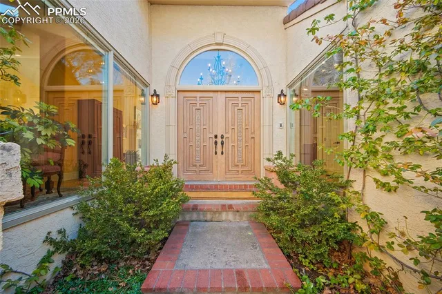 a view of a brick house with a large windows and flower plants