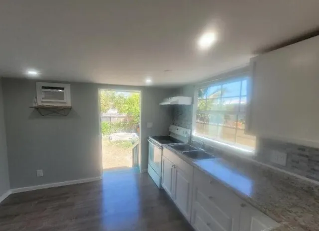 a kitchen with stainless steel appliances granite countertop a stove a sink and a large window